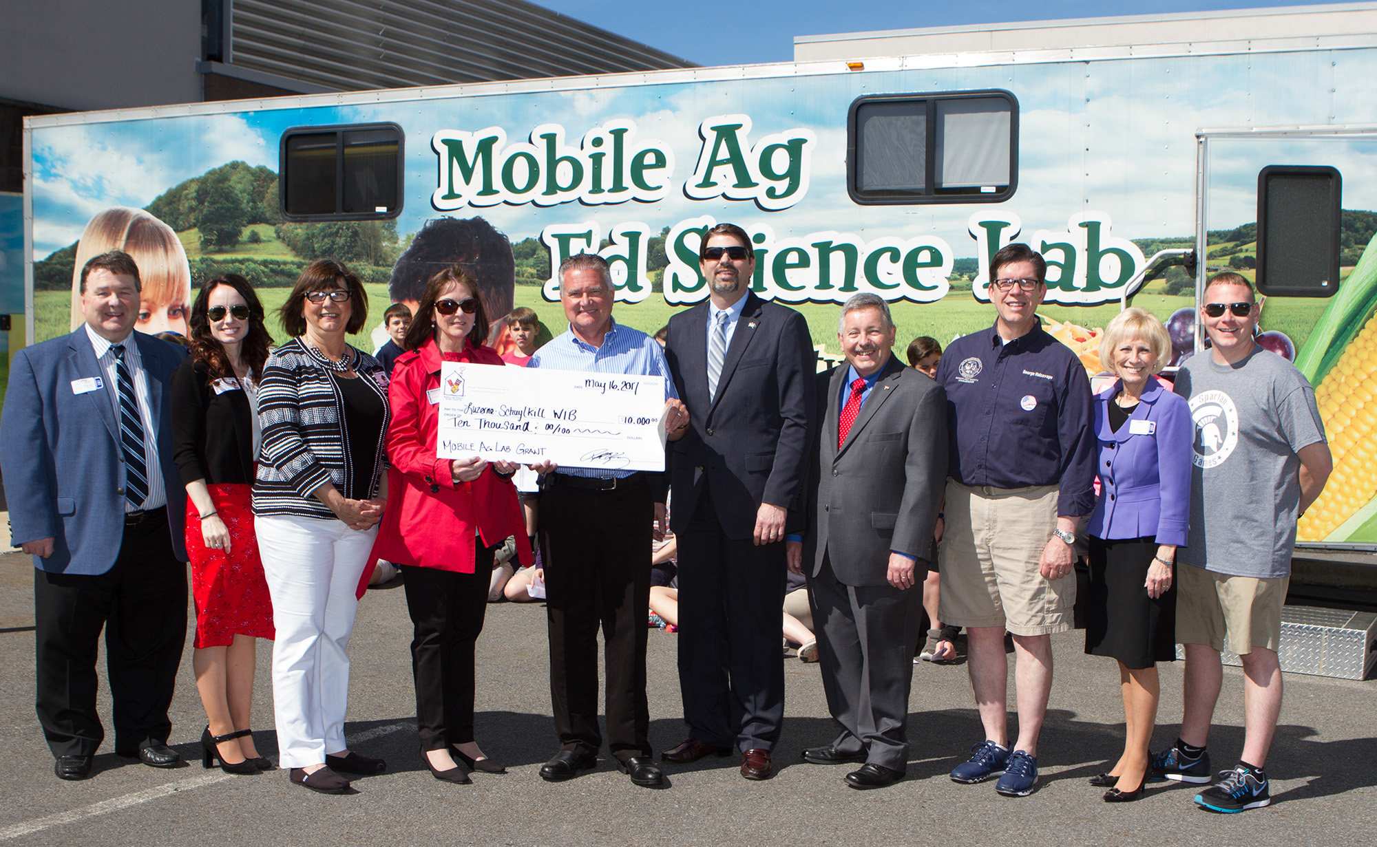 Gregory Hostetter, fourth from the right, the Deputy Secretary for Animal Health & Food Safety at the Pennsylvania Department of Agriculture, visited North Schuylkill Elementary School Tuesday to watch students as they used the Pennsylvania Friends of Agriculture – Mobile Agriculture Education Science Lab. Pictured are, from left: Gary Hess, Schuylkill County commissioner; Courtney Fasnacht, executive director of the Northeast PA Manufacturers and Employers Council, Inc.; Trina Moss, manager for job seekers and employers at the Luzerne/Schuylkill Workforce Investment Board; Patricia Lenahan, executive director of the Luzerne/Schuylkill Workforce Investment Board; Roland Kissinger, McDonald’s owner/operator in Schuylkill County; Hostetter; Robert Carl, president and CEO of the Schuylkill Chamber of Commerce; George Halcovage, Schuylkill County commissioner; Darlene Robbins, president of the Manufacturers and Employers Association; and Robert Ackell, North Schuylkill School District superintendent.